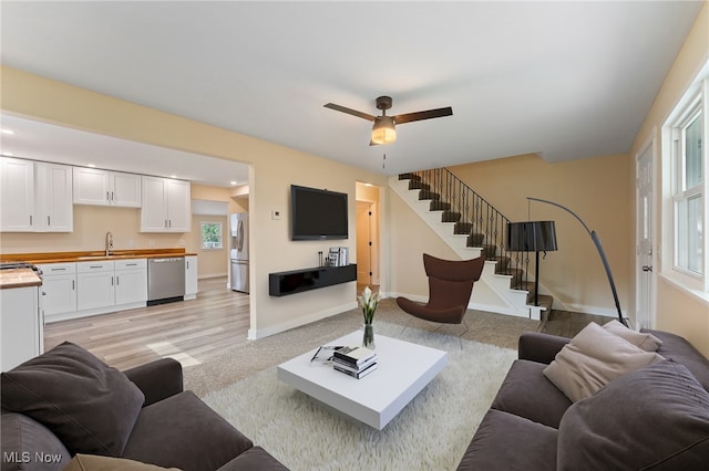 living room with light hardwood / wood-style floors, sink, and ceiling fan