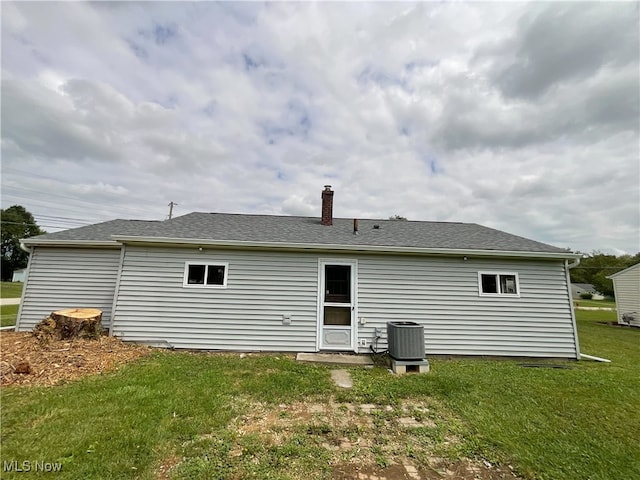 back of property with central AC unit and a lawn