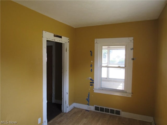 empty room with visible vents, baseboards, and wood finished floors