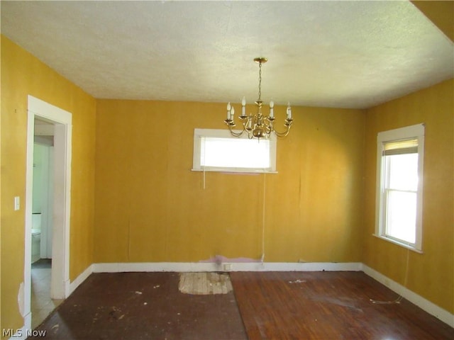 unfurnished dining area with baseboards, plenty of natural light, and a notable chandelier