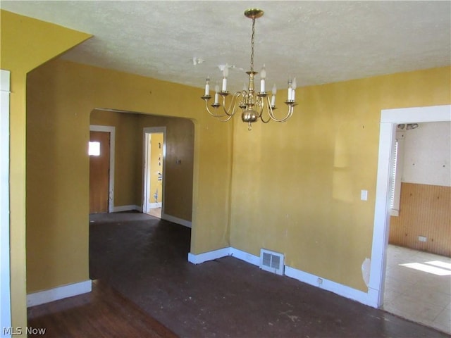 interior space with wood finished floors, visible vents, baseboards, arched walkways, and a notable chandelier