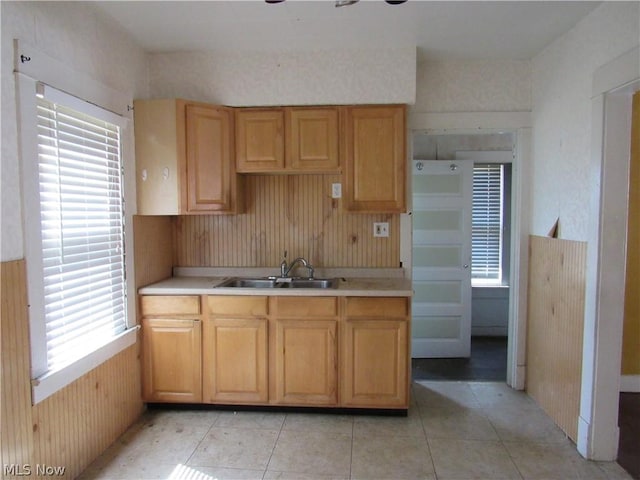 kitchen featuring a sink, wooden walls, light tile patterned floors, and light countertops