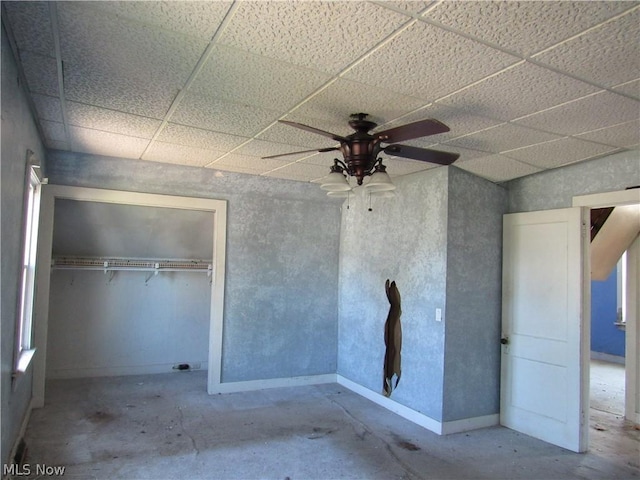 unfurnished bedroom featuring a paneled ceiling, a closet, concrete floors, and ceiling fan