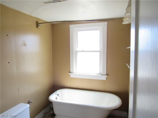 full bathroom featuring a wealth of natural light, a soaking tub, and toilet