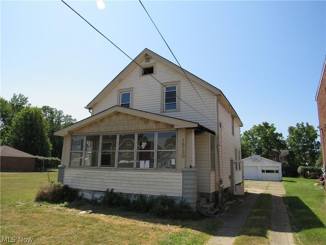 view of front of home with an outbuilding, driveway, a front yard, a sunroom, and a garage