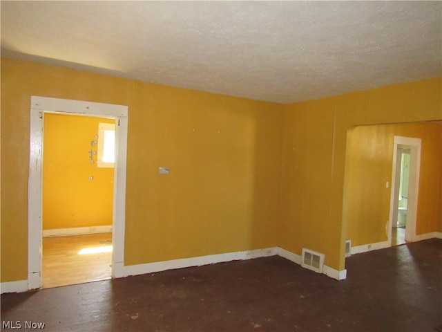 spare room with a textured ceiling and dark hardwood / wood-style floors