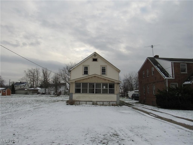 snow covered back of property with a sunroom