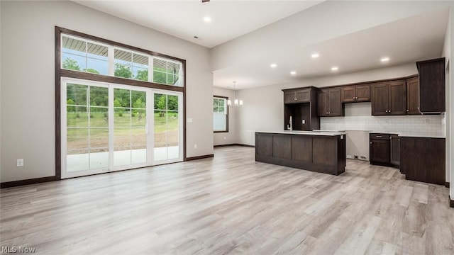 kitchen featuring backsplash, a center island, a chandelier, and light wood-type flooring