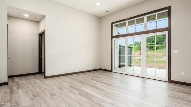 empty room with light hardwood / wood-style floors and a high ceiling