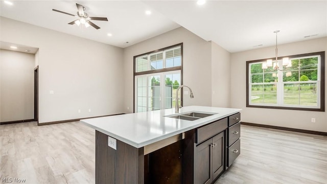 kitchen with dark brown cabinets, sink, a center island with sink, and a wealth of natural light