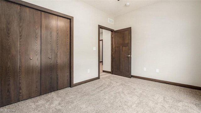 unfurnished bedroom featuring light colored carpet and a closet