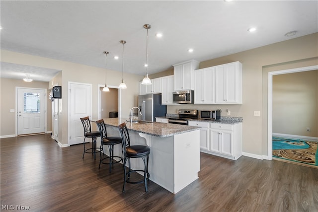 kitchen with dark hardwood / wood-style floors, stainless steel appliances, a kitchen island with sink, and sink