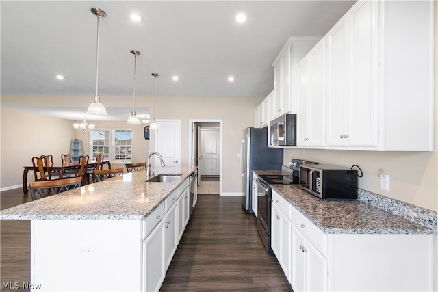 kitchen featuring dark wood-type flooring, stainless steel appliances, light stone countertops, a large island with sink, and sink