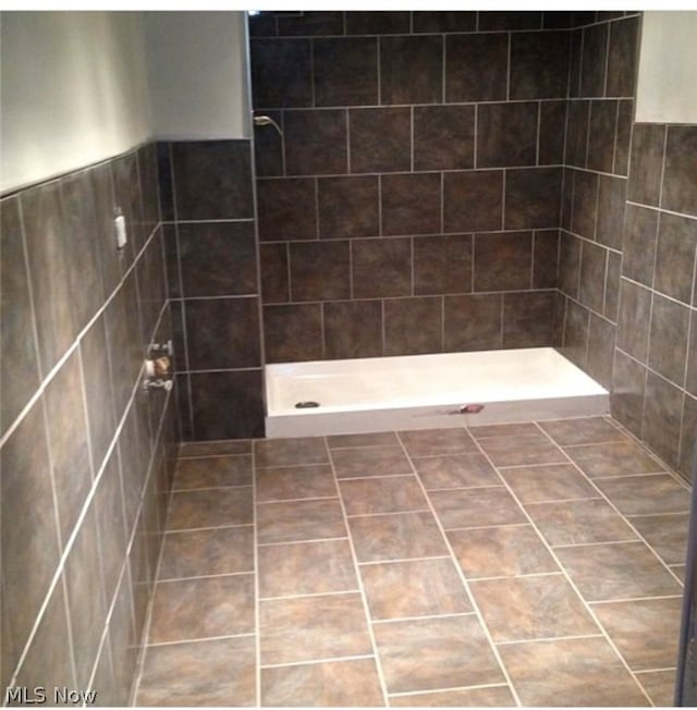 bathroom featuring tile walls, a tile shower, and tile patterned floors