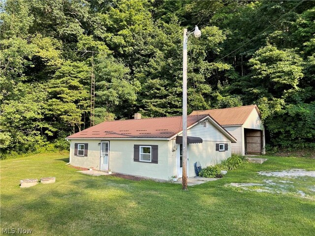 view of side of property with a garage, an outdoor structure, and a lawn