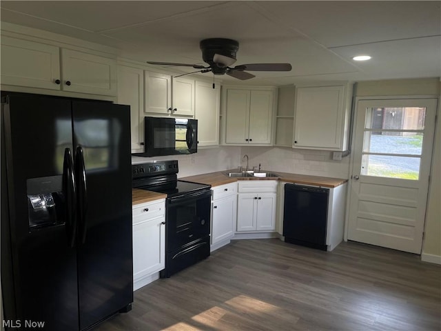 kitchen featuring butcher block counters, sink, white cabinetry, light hardwood / wood-style flooring, and black appliances