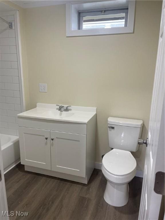 full bathroom featuring vanity, tiled shower / bath, wood-type flooring, and toilet