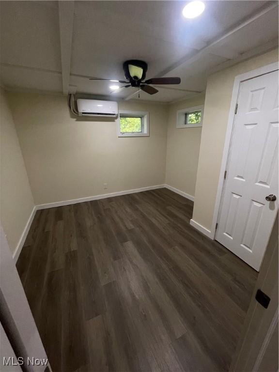 basement with ceiling fan, dark hardwood / wood-style flooring, and an AC wall unit