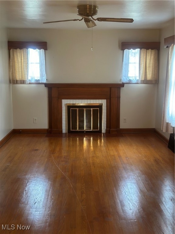 unfurnished living room with plenty of natural light, dark wood-type flooring, and ceiling fan