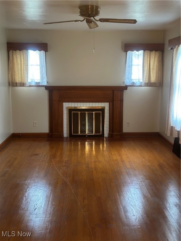 unfurnished living room featuring ceiling fan, a healthy amount of sunlight, and dark hardwood / wood-style floors