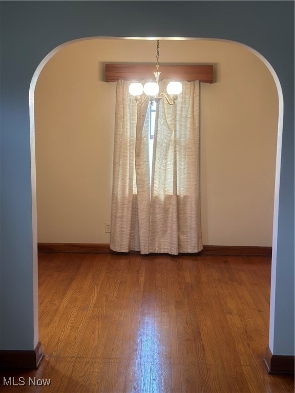 spare room with hardwood / wood-style floors and a chandelier