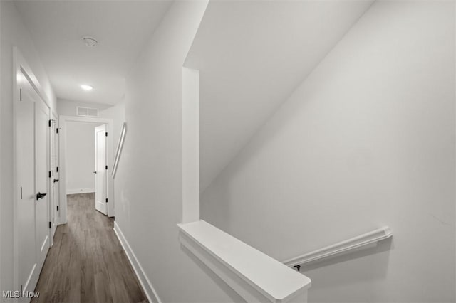 corridor with visible vents, baseboards, and dark wood-style floors