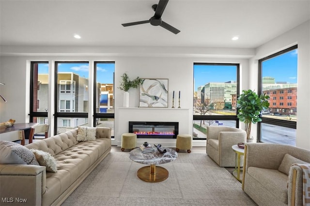 living area with a glass covered fireplace, recessed lighting, and a ceiling fan