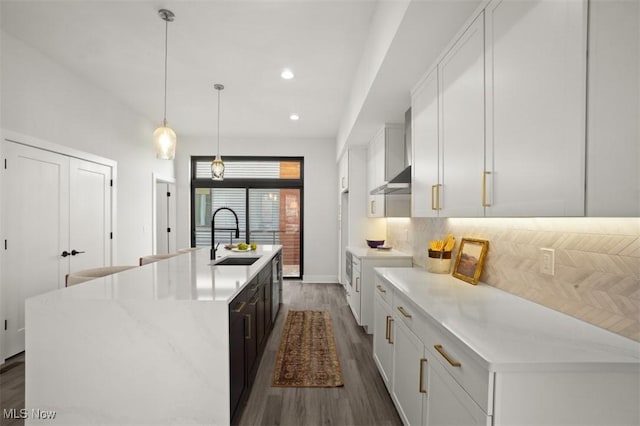 kitchen featuring recessed lighting, an island with sink, white cabinets, dark wood finished floors, and a sink