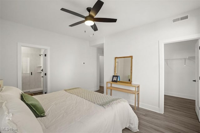bedroom featuring a closet, a spacious closet, visible vents, wood finished floors, and baseboards