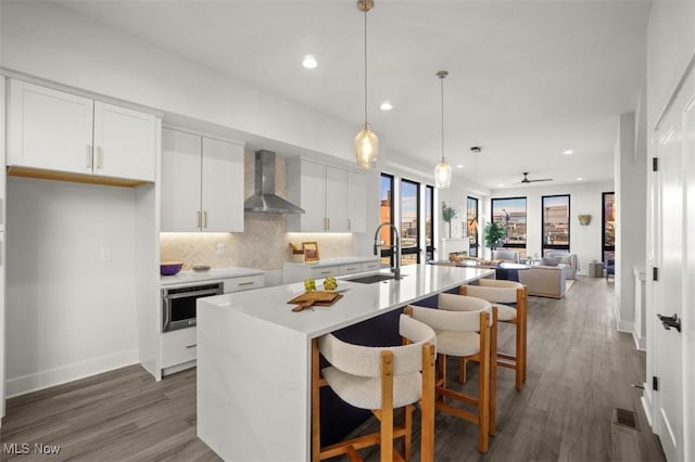kitchen with wall chimney range hood, recessed lighting, a sink, and stainless steel oven