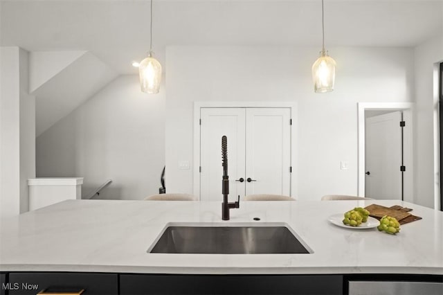kitchen featuring dark cabinets, pendant lighting, vaulted ceiling, and a sink