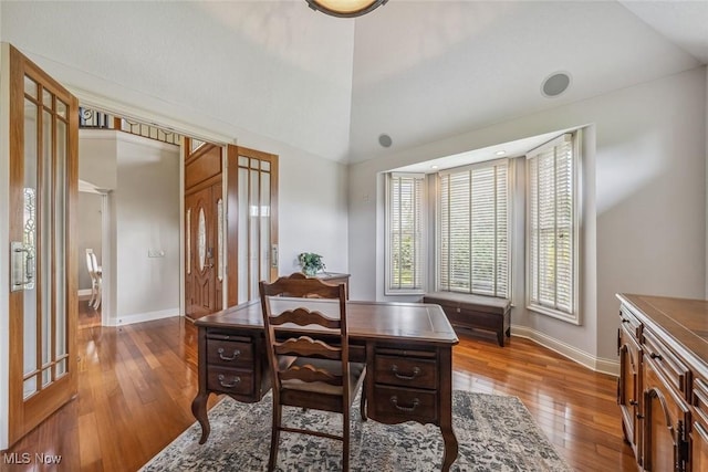 dining space with lofted ceiling, hardwood / wood-style flooring, and baseboards