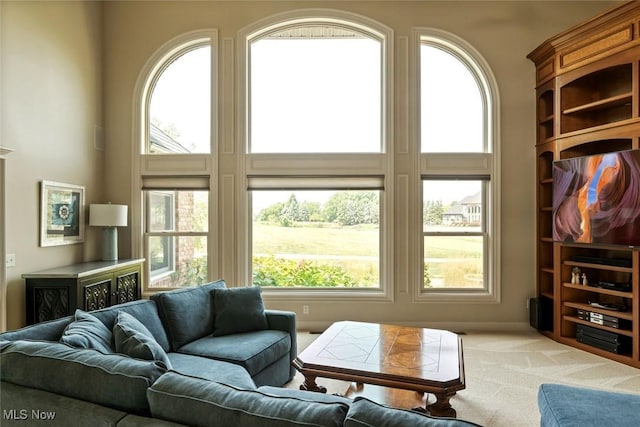 living room with light colored carpet, a healthy amount of sunlight, and a towering ceiling