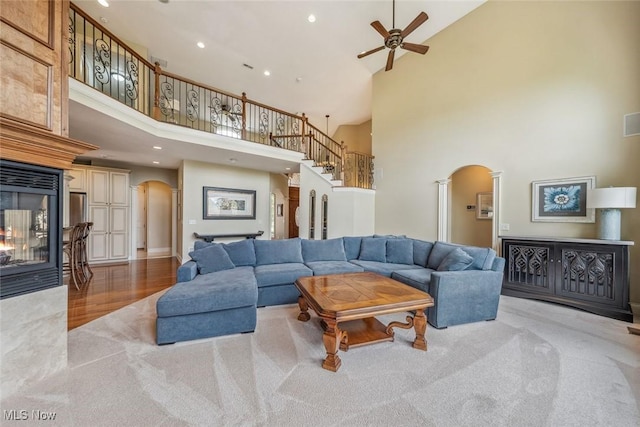 living area with a multi sided fireplace, arched walkways, a high ceiling, and visible vents