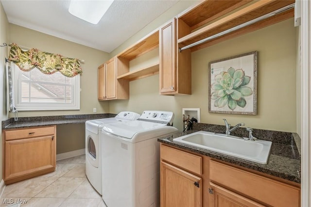 clothes washing area with cabinet space, light tile patterned floors, washing machine and dryer, and a sink