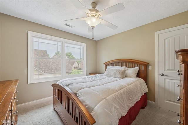 bedroom with visible vents, a textured ceiling, carpet floors, baseboards, and ceiling fan