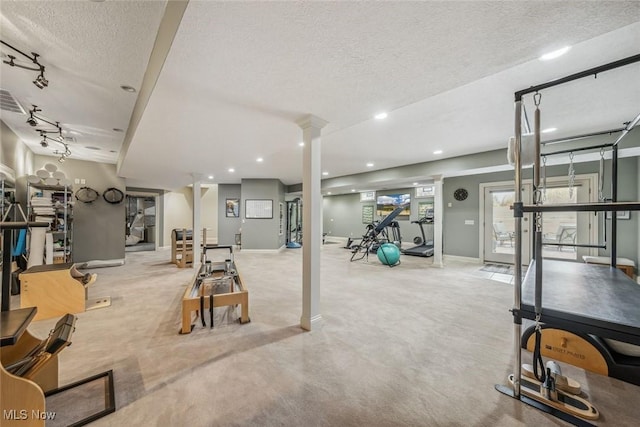 interior space with a textured ceiling, recessed lighting, rail lighting, decorative columns, and baseboards