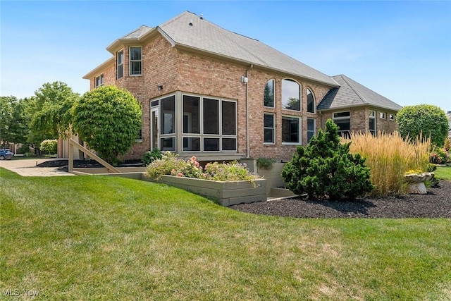 rear view of property with brick siding and a yard