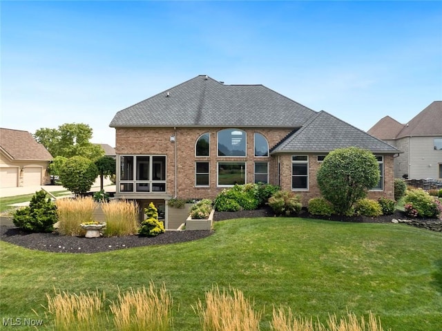 rear view of property featuring a yard and brick siding