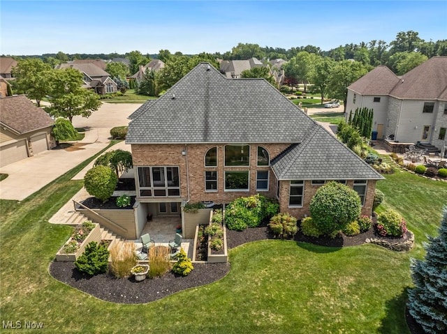 back of property with brick siding, a garage, a residential view, and a yard