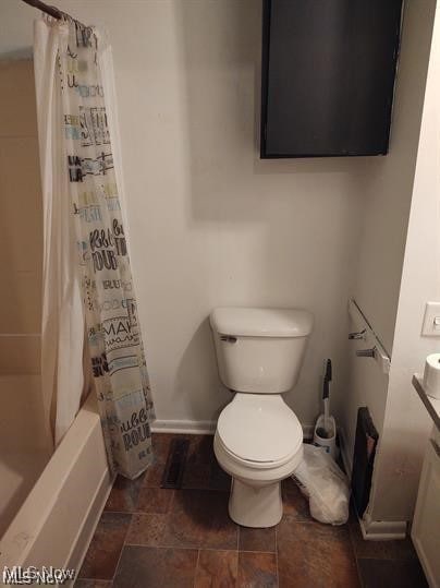 bathroom featuring shower / bathtub combination with curtain and toilet