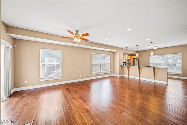 unfurnished living room with hardwood / wood-style flooring and ceiling fan