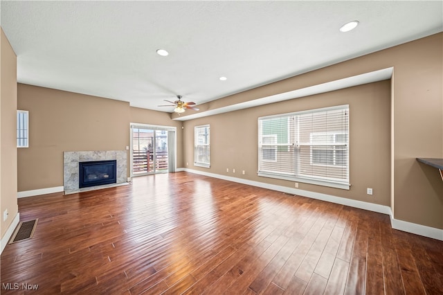 unfurnished living room featuring a high end fireplace, ceiling fan, and dark hardwood / wood-style flooring