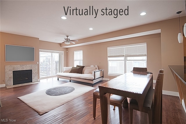 dining room featuring dark hardwood / wood-style flooring, ceiling fan, and a high end fireplace