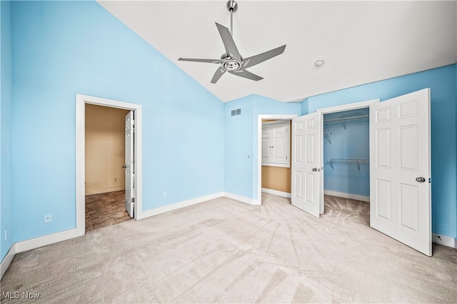 unfurnished bedroom with light carpet, a closet, high vaulted ceiling, and ceiling fan