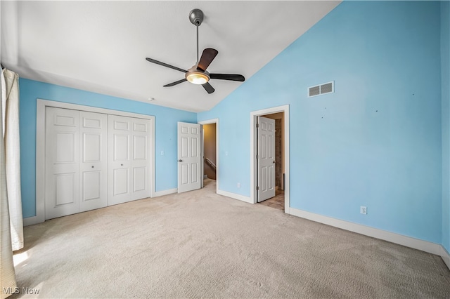 unfurnished bedroom featuring light carpet, a closet, high vaulted ceiling, and ceiling fan