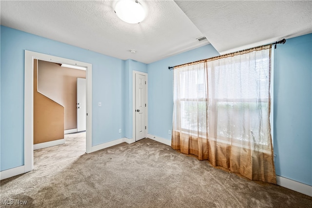 carpeted spare room featuring a textured ceiling