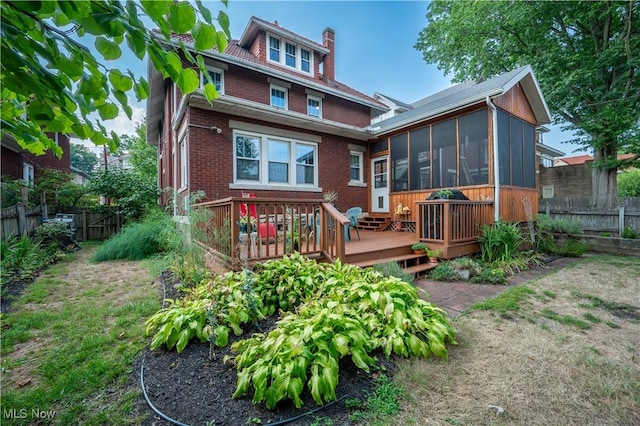 rear view of property with a wooden deck and a sunroom