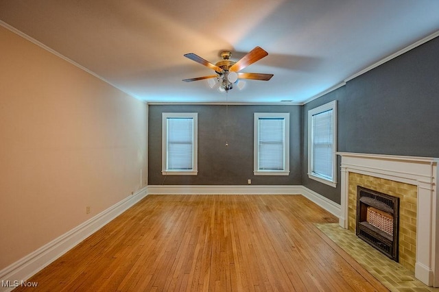 unfurnished living room featuring a tiled fireplace, ceiling fan, light hardwood / wood-style floors, and crown molding