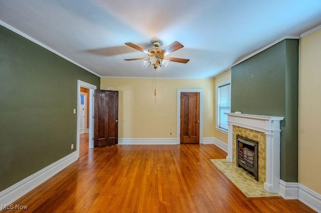 unfurnished living room with ceiling fan, light wood-type flooring, a brick fireplace, and crown molding